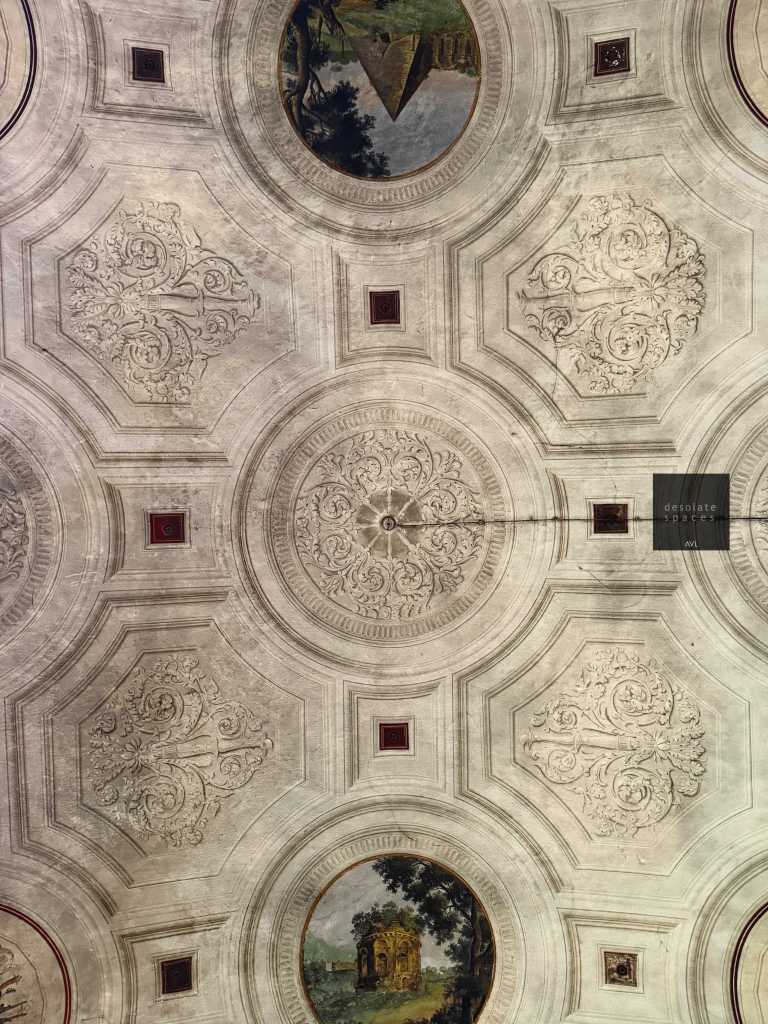Soffitto decorato con motivi ornamentali e dipinti circolari paesaggistici.